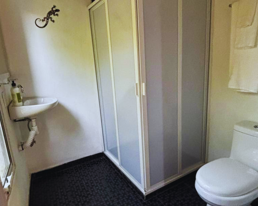 Distribución del baño privado con regadera de agua caliente en el hospedaje familiar Habitación Primavera