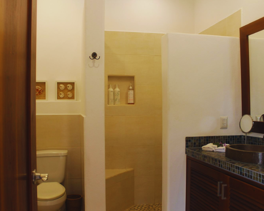 Baños completos limpios y regadera exterior en área de alberca